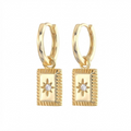 Gold-toned star medallion huggie earrings detail - luxury hoop earrings with ridged border rectangular pendant and crystal center - close-up product photography