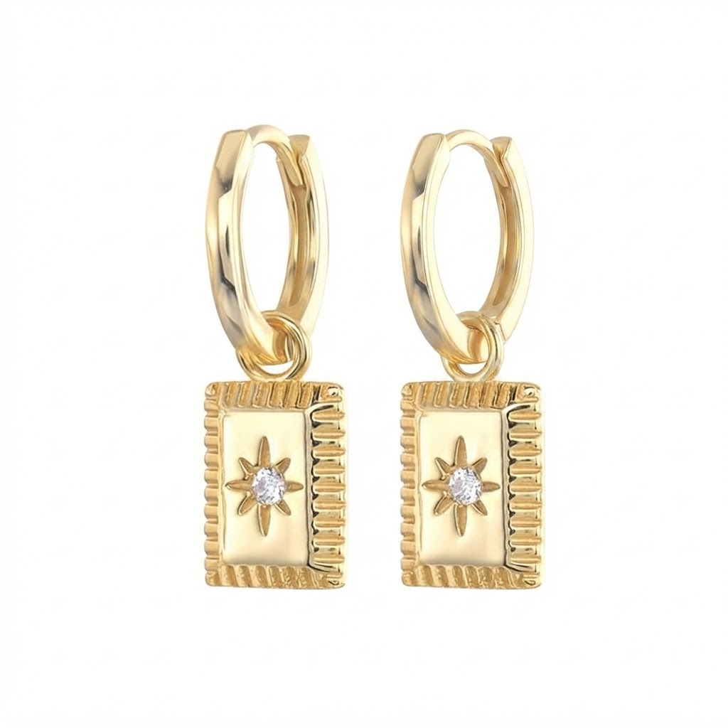 Gold-toned star medallion huggie earrings detail - luxury hoop earrings with ridged border rectangular pendant and crystal center - close-up product photography