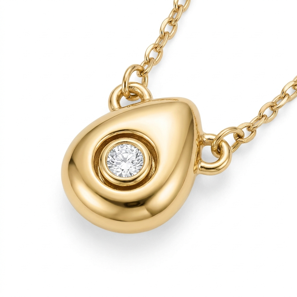 gold-toned puffy teardrop pendant with rotating crystal detail – three-dimensional organic droplet with movable bezel-set crystal in circular concave setting – extreme macro close-up product photography