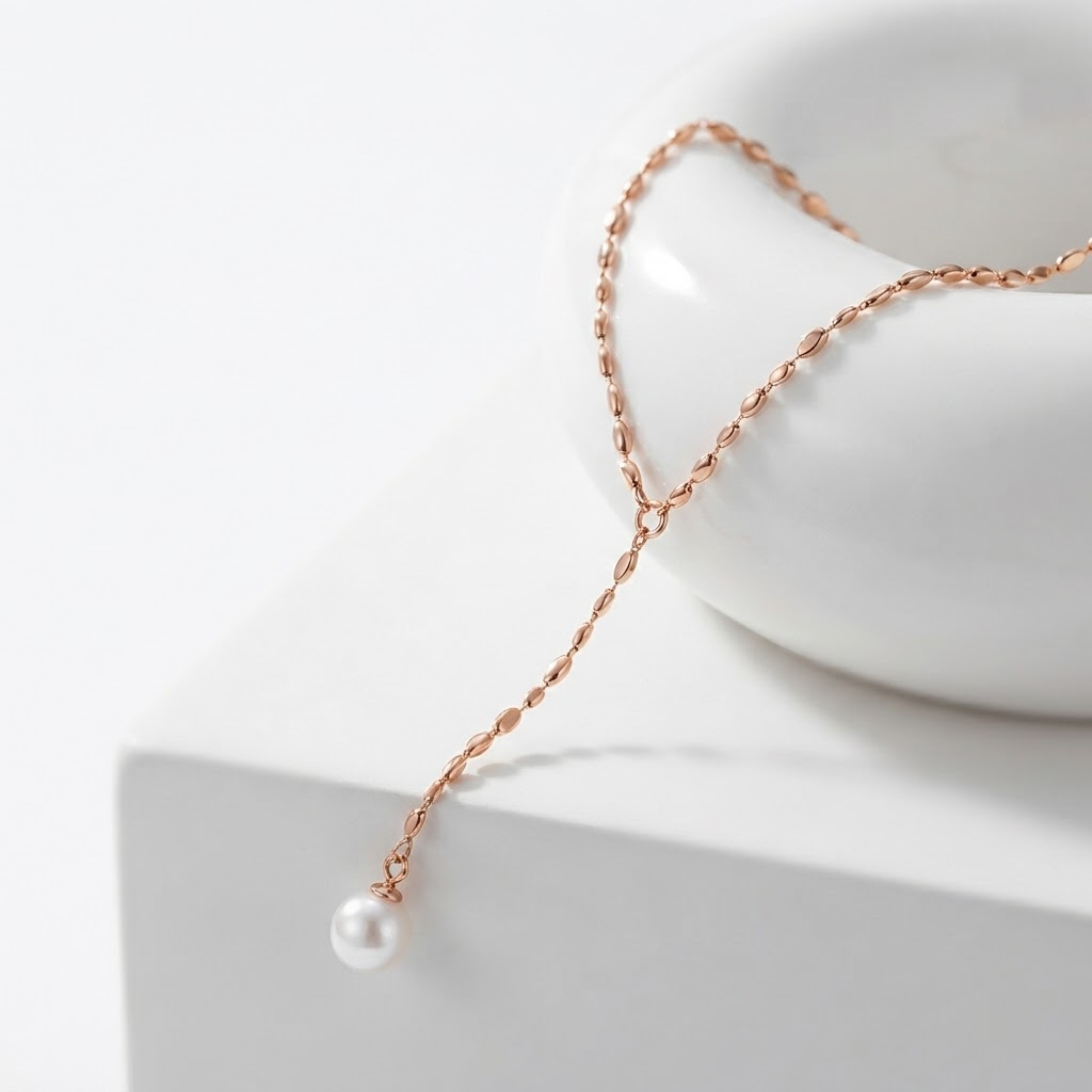 Rose gold-toned Y-lariat necklace with faux pearl detail - luxury adjustable drop necklace with beaded chain - close-up product photography
