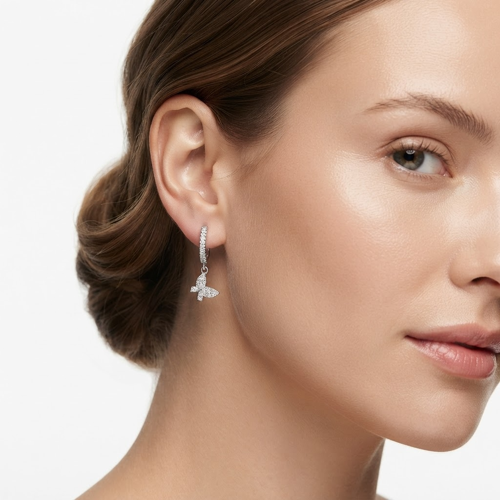 Woman wearing silver-toned huggie hoop earrings with pavé crystals and butterfly charm - elegant crystal huggie earrings styling photo - luxury jewelry lifestyle photography