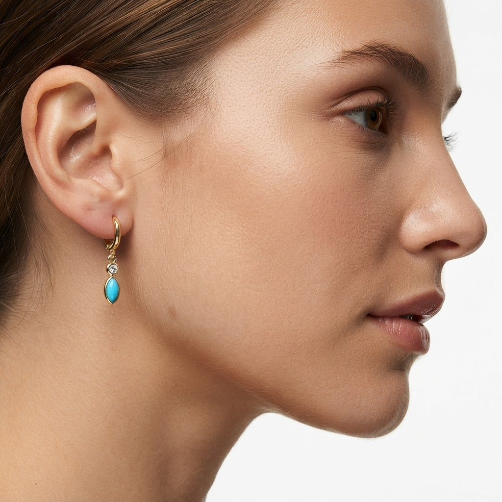 Woman wearing gold-toned huggie hoop earrings with turquoise marquise stone and crystal - elegant turquoise drop earrings styling photo - luxury jewelry lifestyle photography