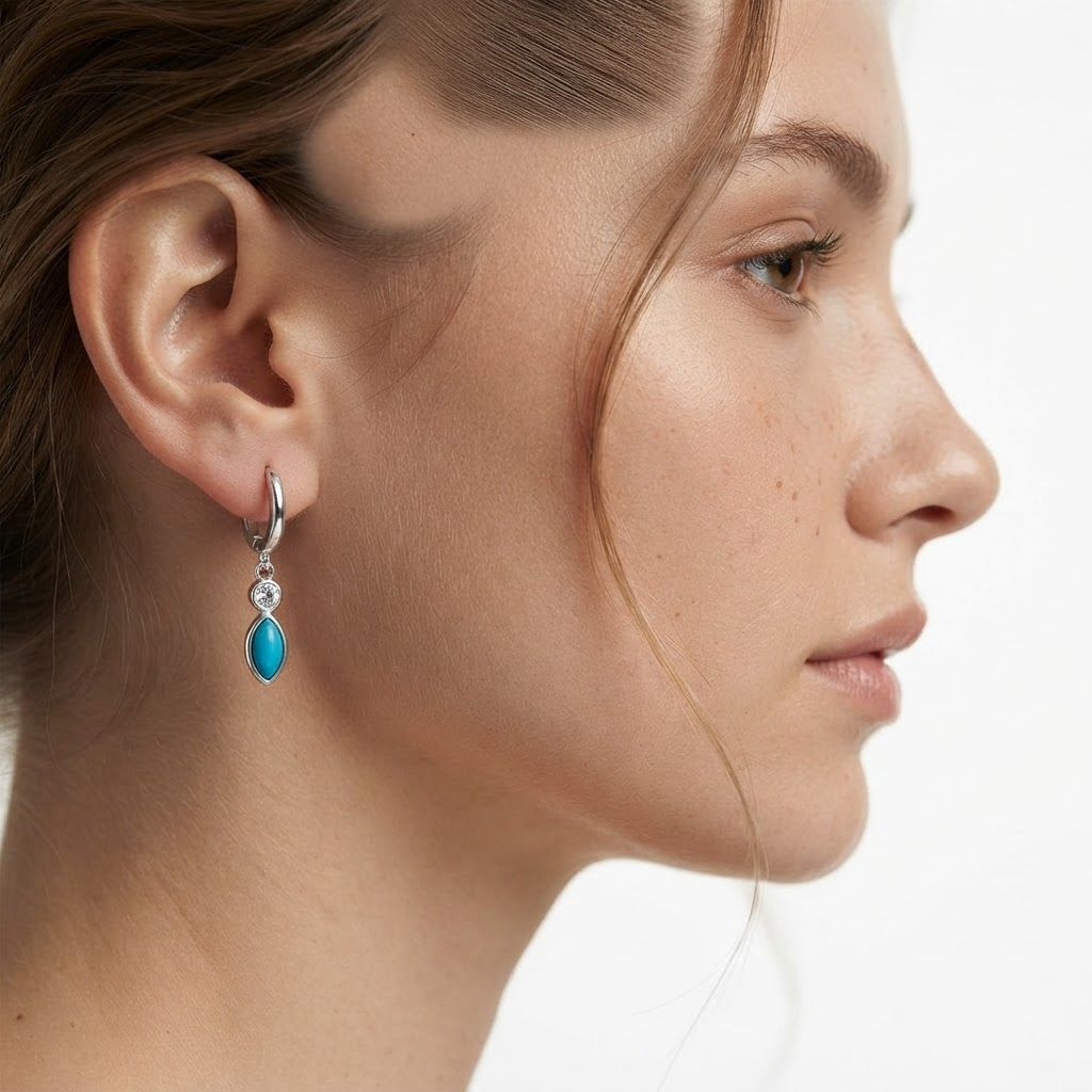 Woman wearing silver-toned huggie hoop earrings with turquoise marquise stone and crystal - elegant turquoise drop earrings styling photo - luxury jewelry lifestyle photography