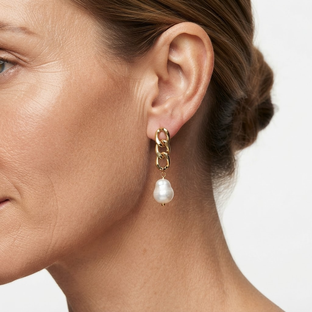 Woman wearing gold-toned chunky chain link stud earrings with baroque faux pearl drop - bold modern chain and pearl earrings styling photo - luxury jewelry lifestyle photography