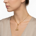 Woman wearing gold-toned adjustable bolo necklace with heart-shaped charms - elegant heart necklace styling photo - luxury jewelry lifestyle photography
