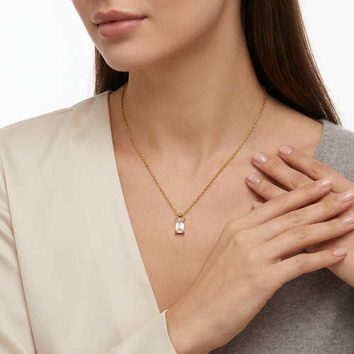 Woman wearing gold-toned stainless steel cable chain necklace with emerald - elegant necklace styling photo - luxury jewelry lifestyle photography

