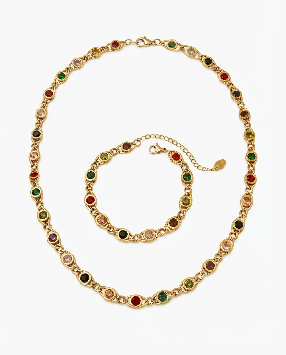 Matching jewelry set with gold-tone necklace and bracelet featuring multicolored round gemstones in red, green, pink, yellow, purple, black and peach on white studio background