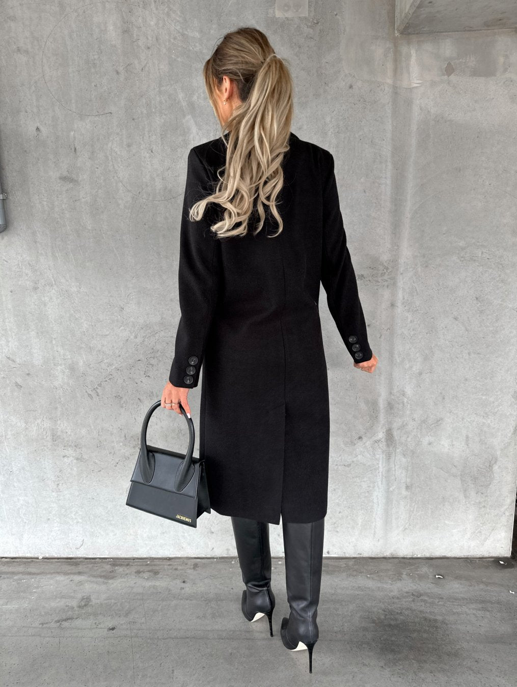 Model wearing black double-breasted coat with handbag