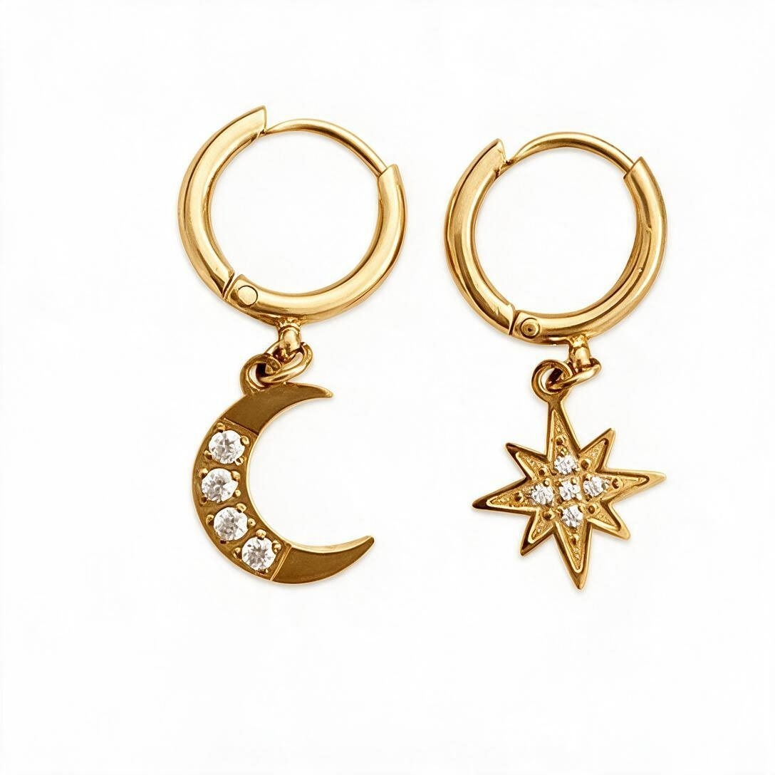 Gold-tone hinged hoop earrings with dangling moon and star charms set with clear crystals, studio white background
