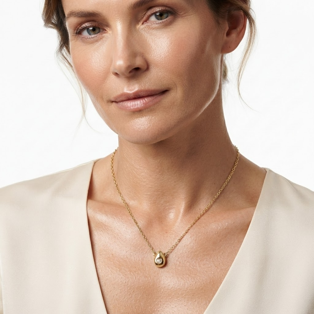 Woman wearing gold-toned delicate necklace with puffy teardrop rotating crystal pendant – minimalist 3D droplet necklace with moving crystal styling photo – Harper's Bazaar luxury jewelry lifestyle photography