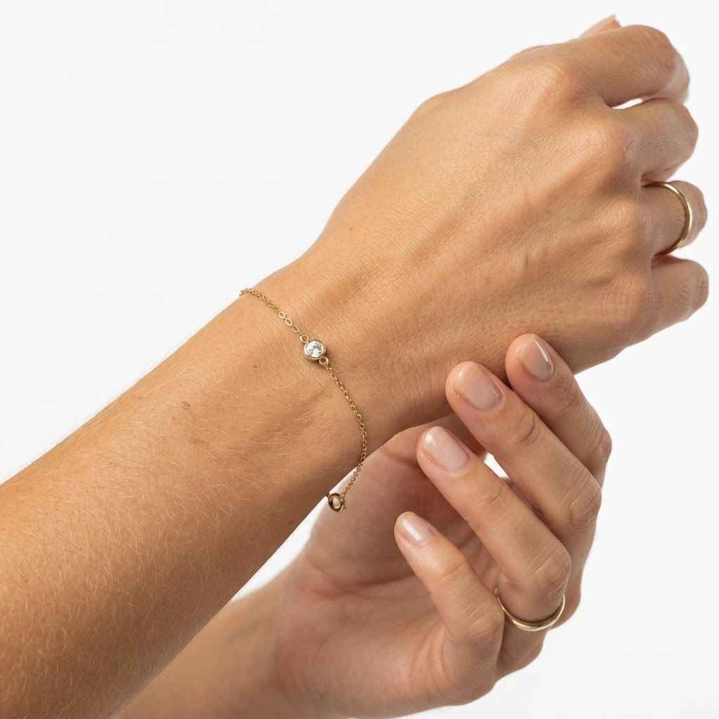 Woman wearing gold-toned delicate cable chain bracelet with bezel crystal charm – elegant minimalist bracelet styling photo – luxury jewelry lifestyle photography